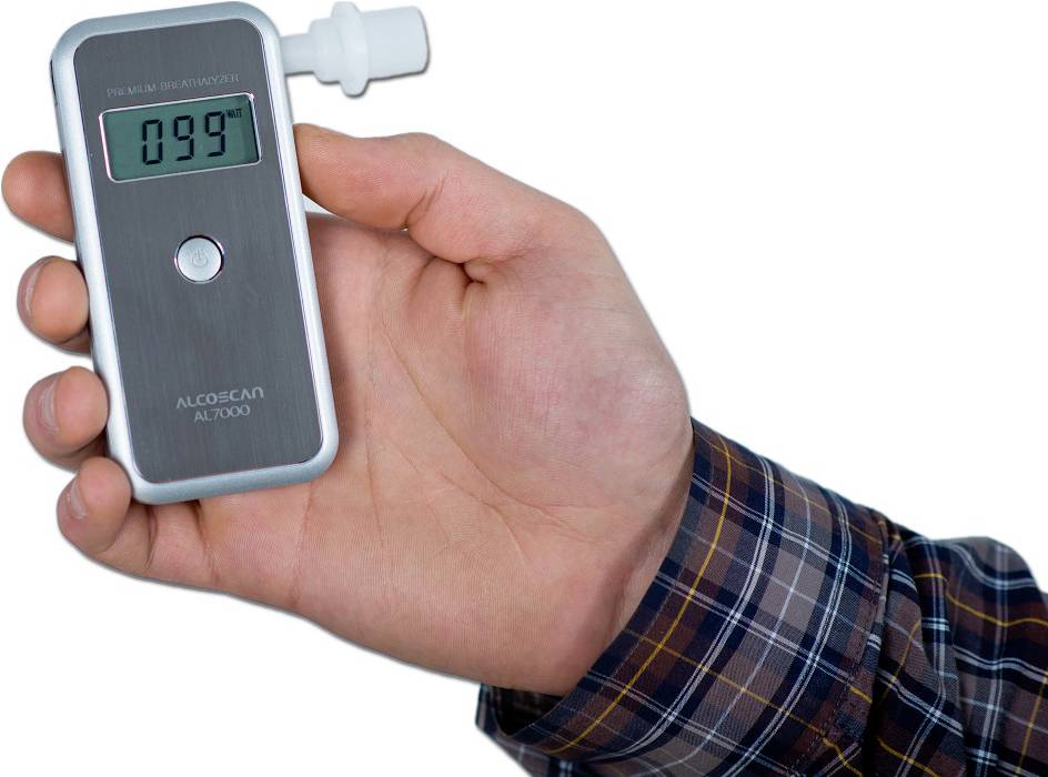 Eine Hand hält ein Atemalkoholmessgerät mit einem digitalen Display, das '0.99' anzeigt. Das Gerät ist zur Alkoholmessung geliefert.