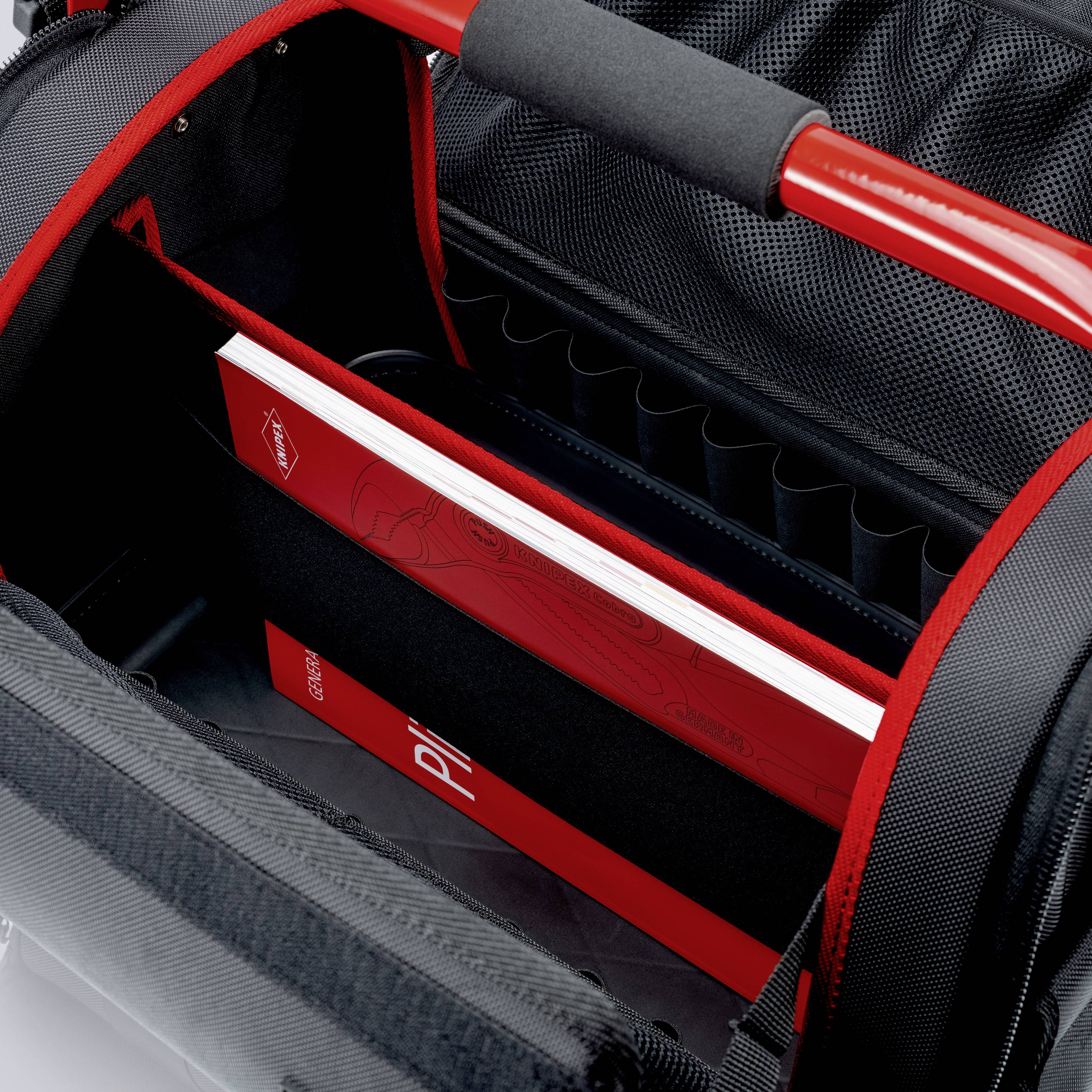 Kameratasche mit gepolsterten Fächern, zeigt ein rotes Buch in einem der Fächer. Die Tasche hat schwarze und rote Details.