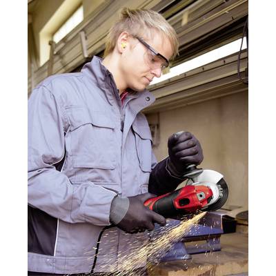 Ein Mann in Schutzbrille und Handschuhen schleift Metall mit einem Winkelschleifer in einer Werkstatt. Funken sprühen beim Schleifen.