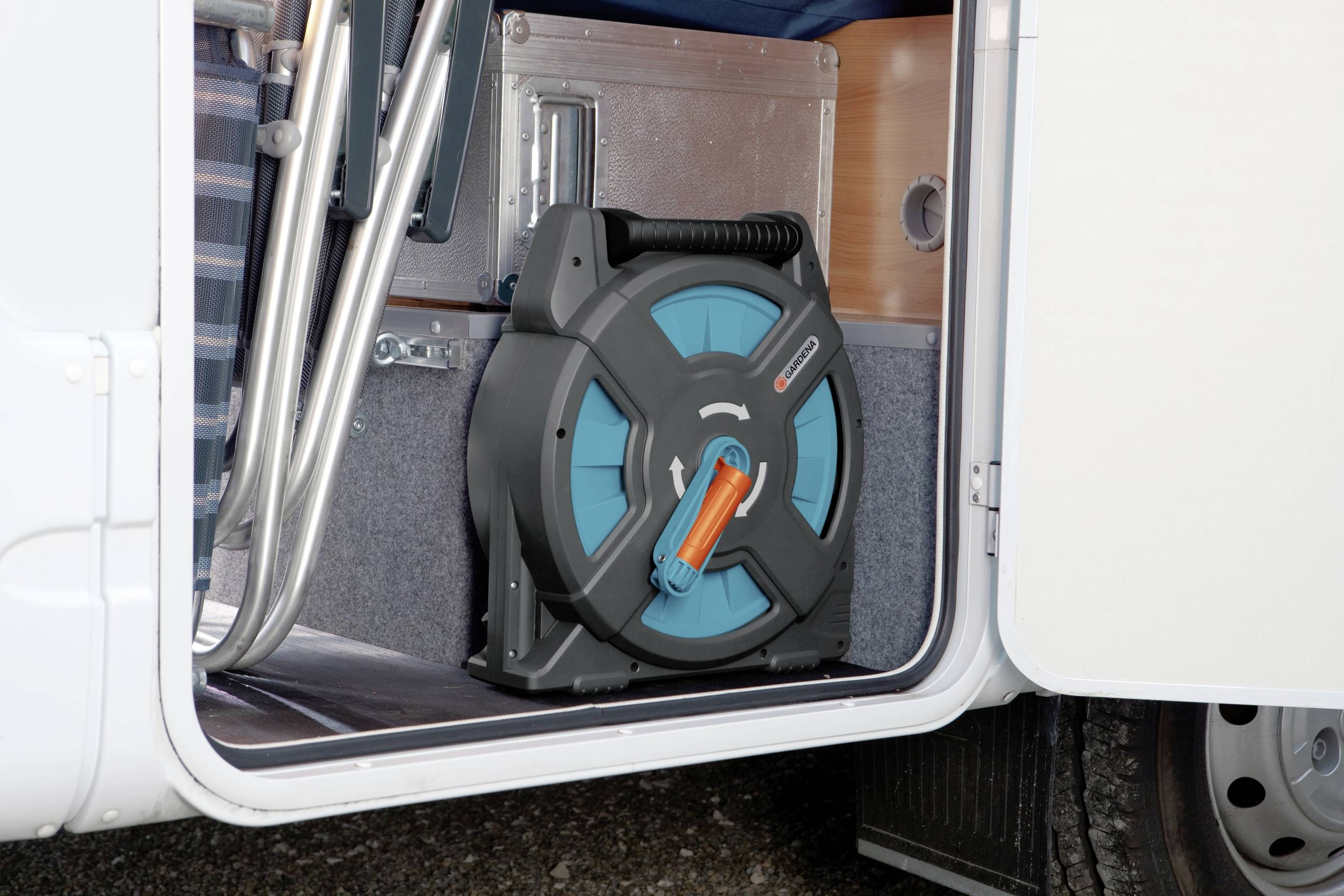 Ein aufgerolltes Verlängerungskabel liegt in einem offenen Fach eines Wohnmobils. Das Kabel ist blau und orange, die Halterung schwarz.