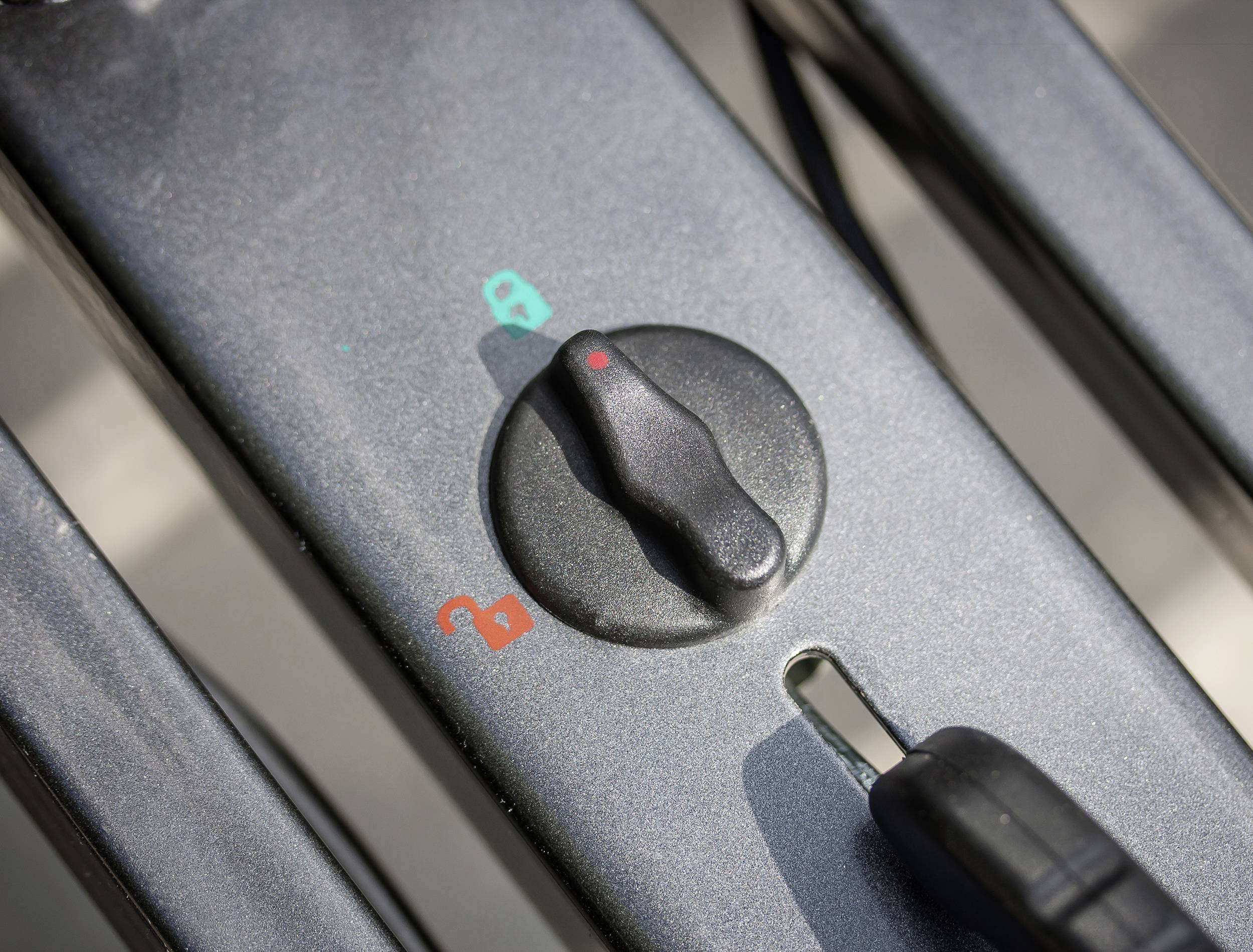 Ein Drehknopf an einem Fahrradschloss zeigt Symbole für geöffnet (rotes Schloss) und geschlossen (grünes Schloss).