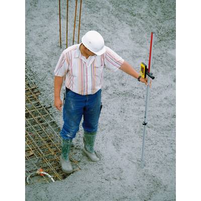 Ein Bauarbeiter in Schutzkleidung steht auf einer Betonfläche und hält ein Vermessungsgerät, um die Betonhöhe zu überprüfen.