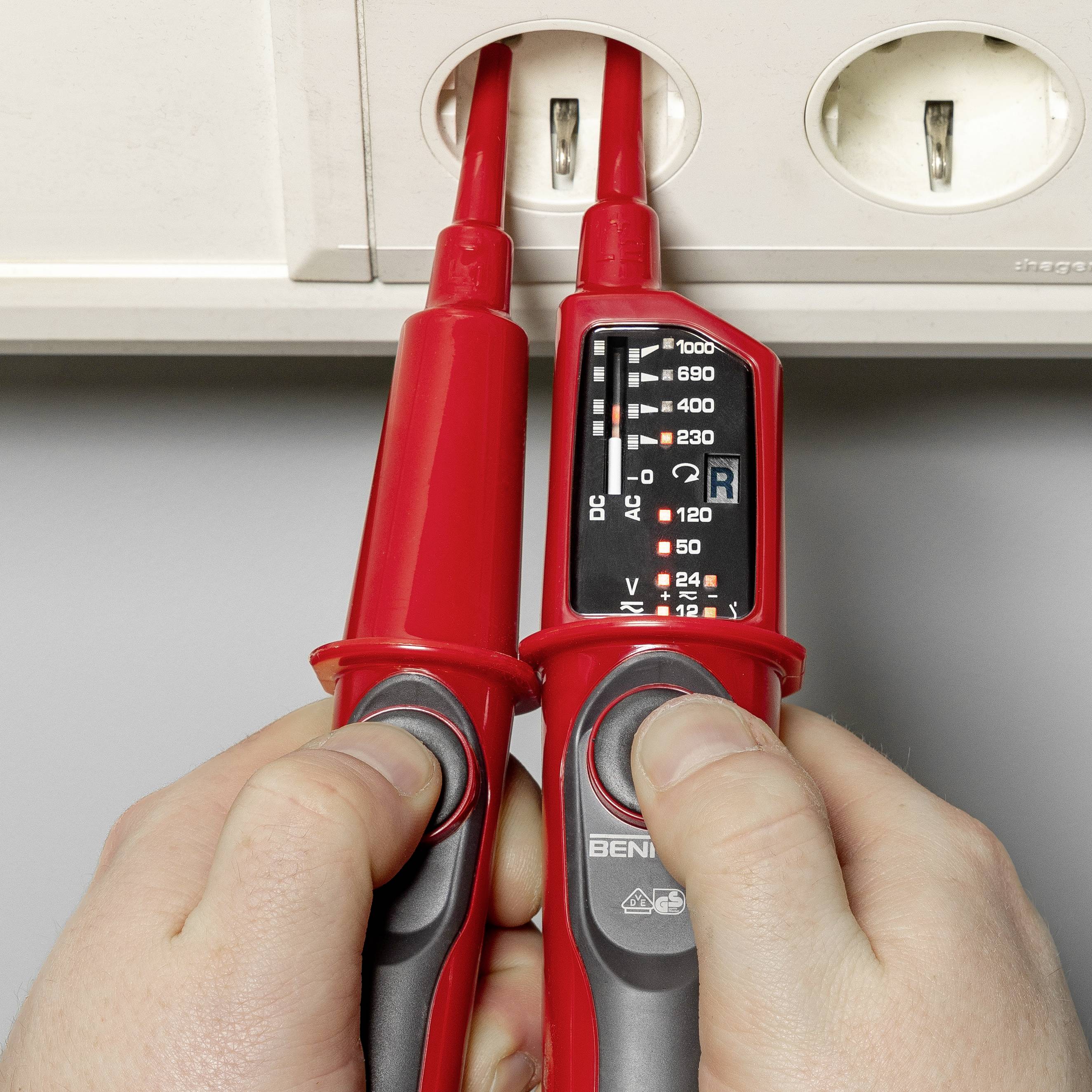 Eine Person verwendet ein Multimeter, um die Spannung in einer Steckdose zu messen. Das Display zeigt den Spannungswert an.