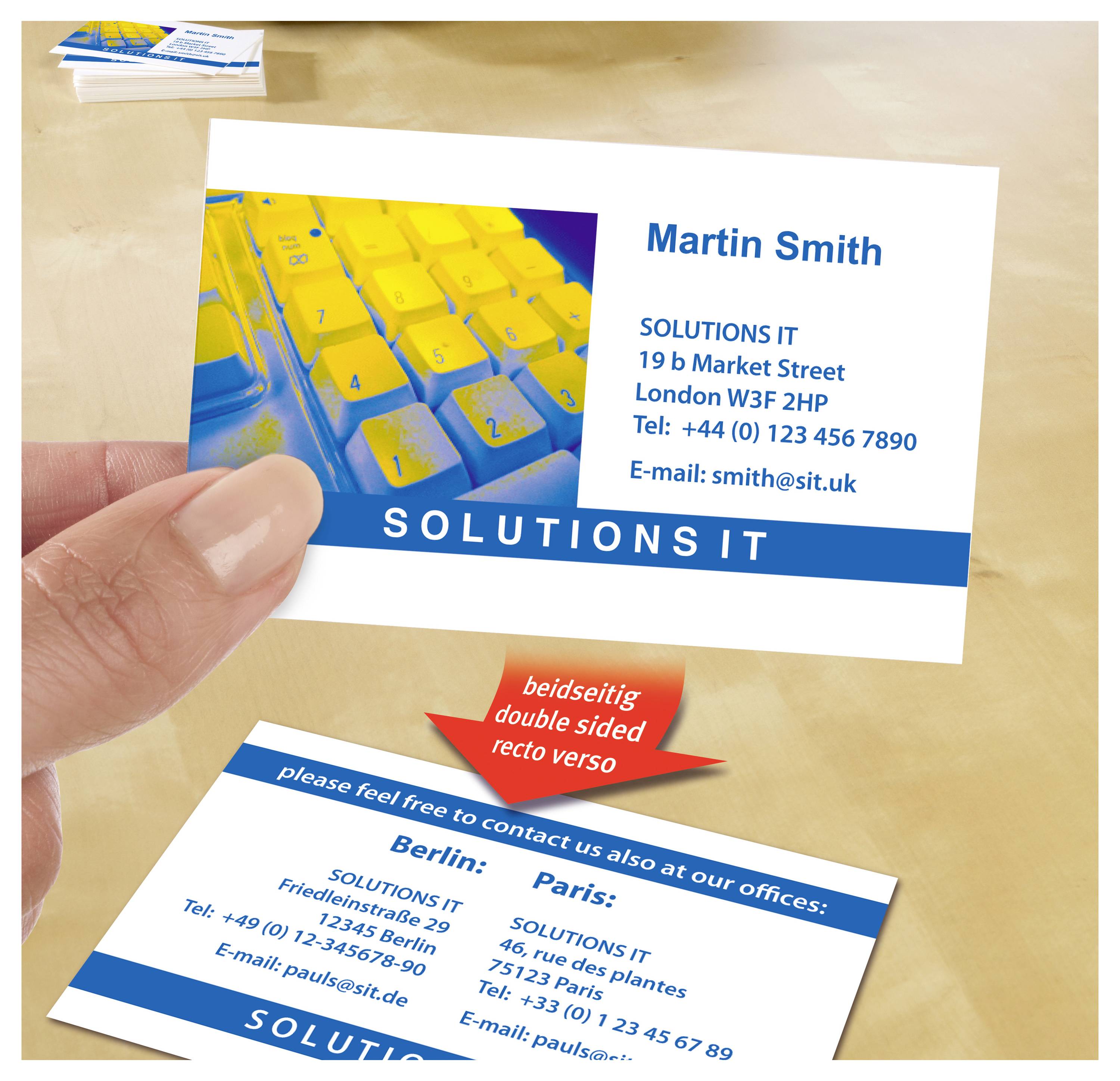 Visitenkarte für Martin Smith von SOLUTIONS IT mit Kontaktdaten; unten Rückseite mit Büroadressen in Berlin und Paris, Pfeil zeigt beidseitiges Design.