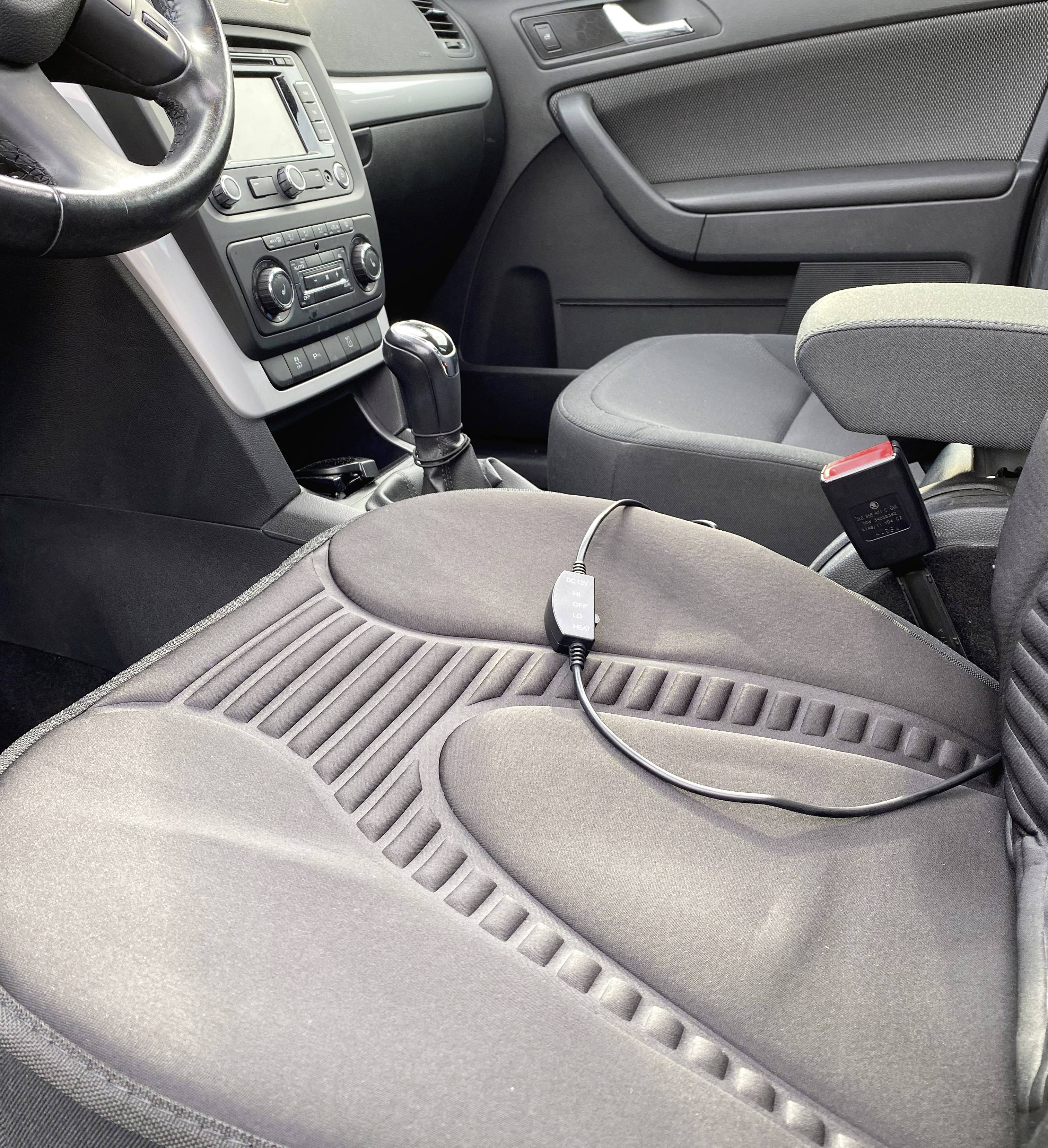 Ein geparktes Auto zeigt den Innenraum, inklusive Sitz und Armaturenbrett. Auf dem Sitz liegt ein Ladekabel.