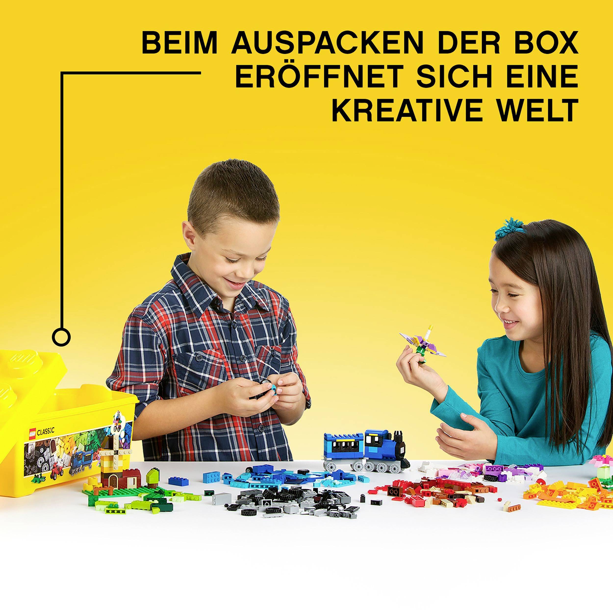 Ein Junge und ein Mädchen spielen mit bunten Bausteinen. Sie lächeln und zeigen Freude. Text oben: 'Beim Auspacken der Box eröffnet sich eine kreative Welt'.