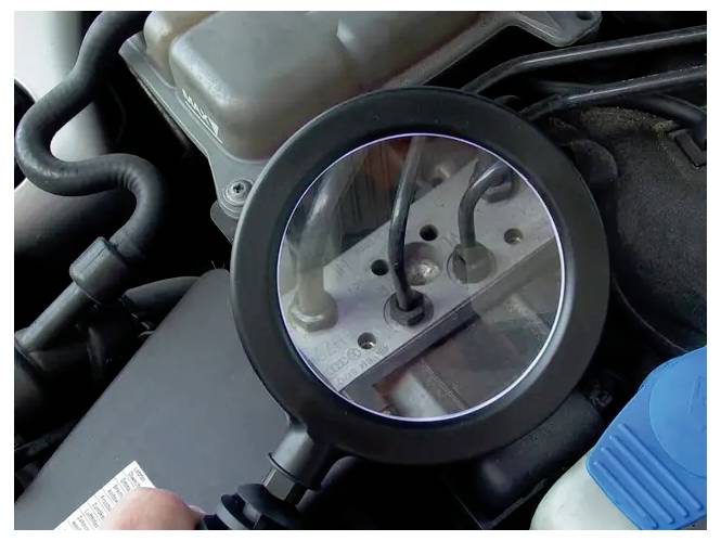 Lupe, die Motorkomponenten und Verbindungen unter der Motorhaube eines Autos hervorhebt und den Fokus auf die Inspektionen von Automechanik anzeigt.