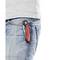 Ein rot-schwarzes Klappmesser steckt in der Gesäßtasche einer blauen Jeans. Der Markenname ist auf dem Messer sichtbar.