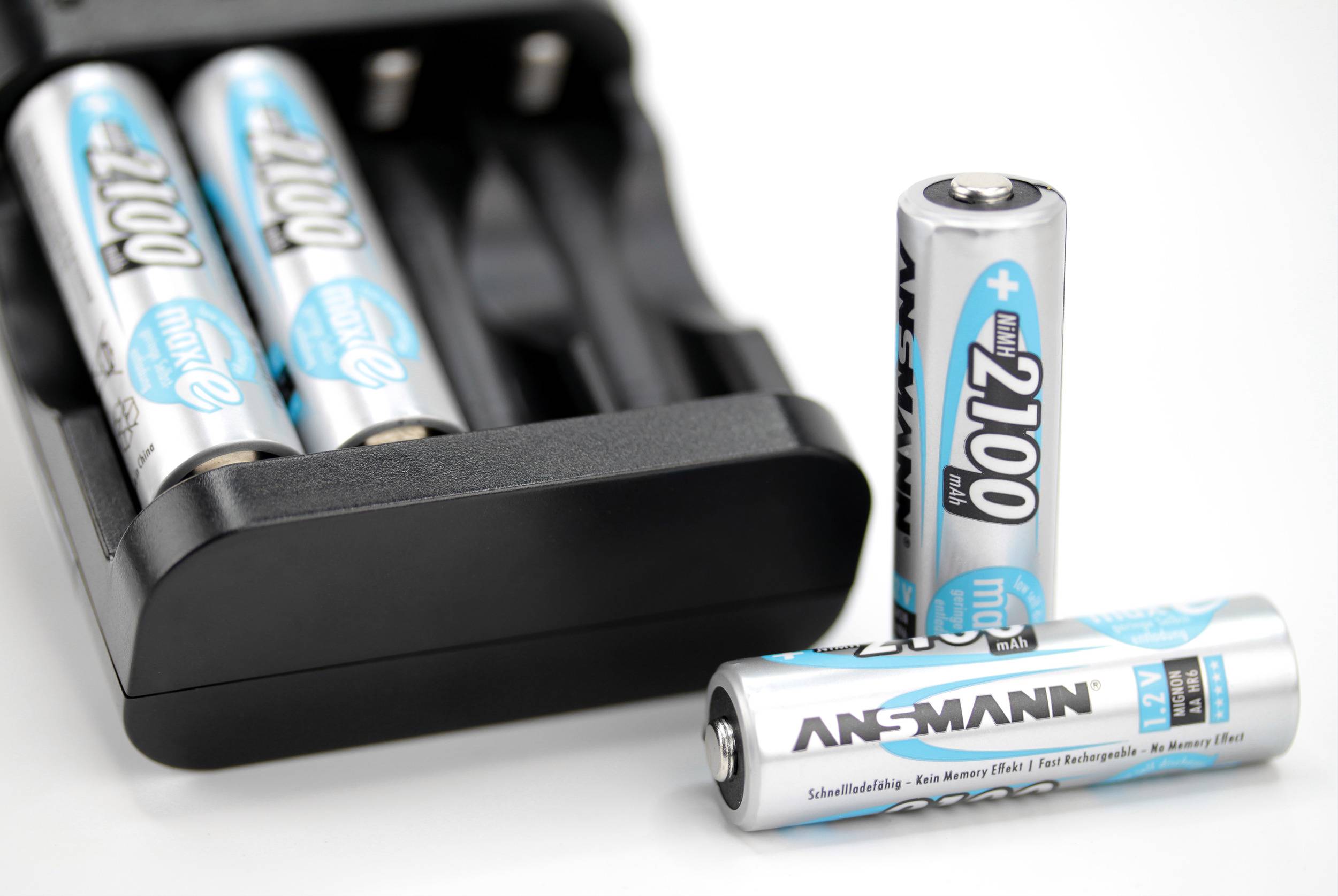 Zwei AA-Batterien im Ladegerät, zwei weitere daneben stehend mit der Aufschrift 'ANSMANN'.