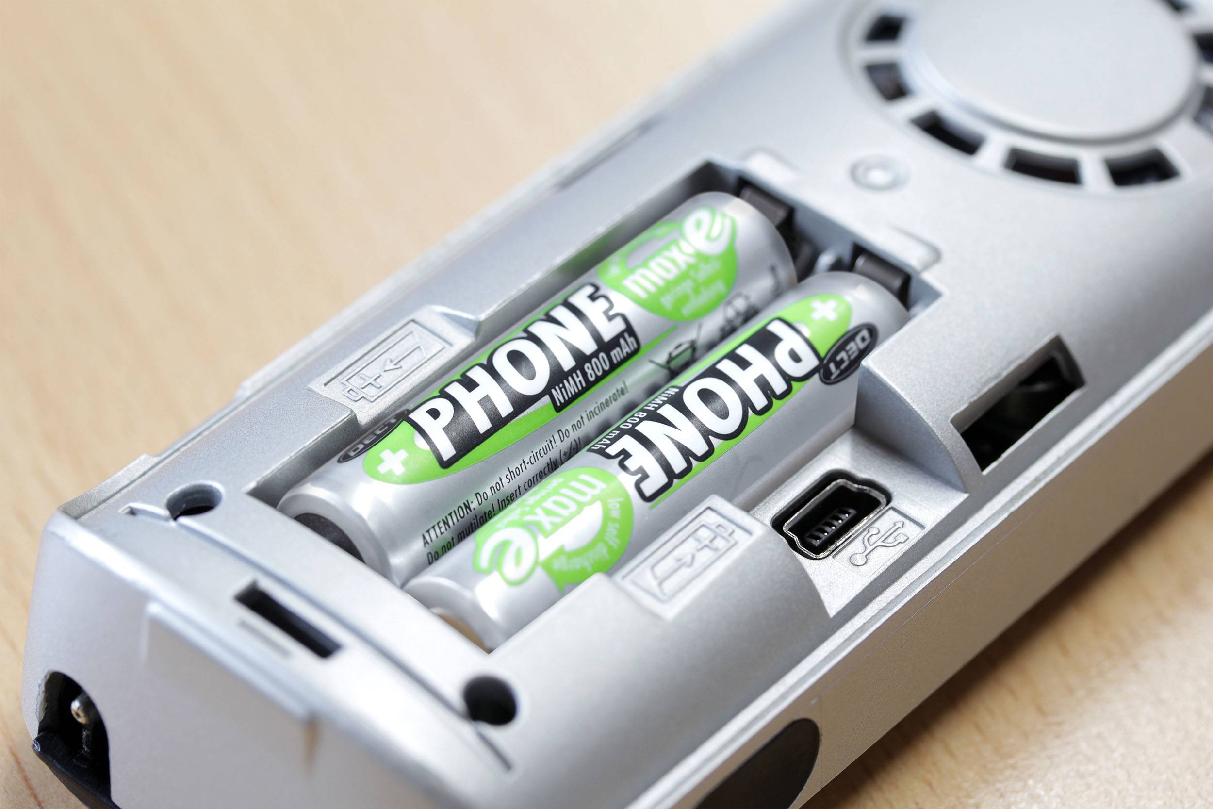 Ein Fernbedienungsrücken zeigt zwei eingelegte AA-Batterien mit der Aufschrift 'PHONE'.