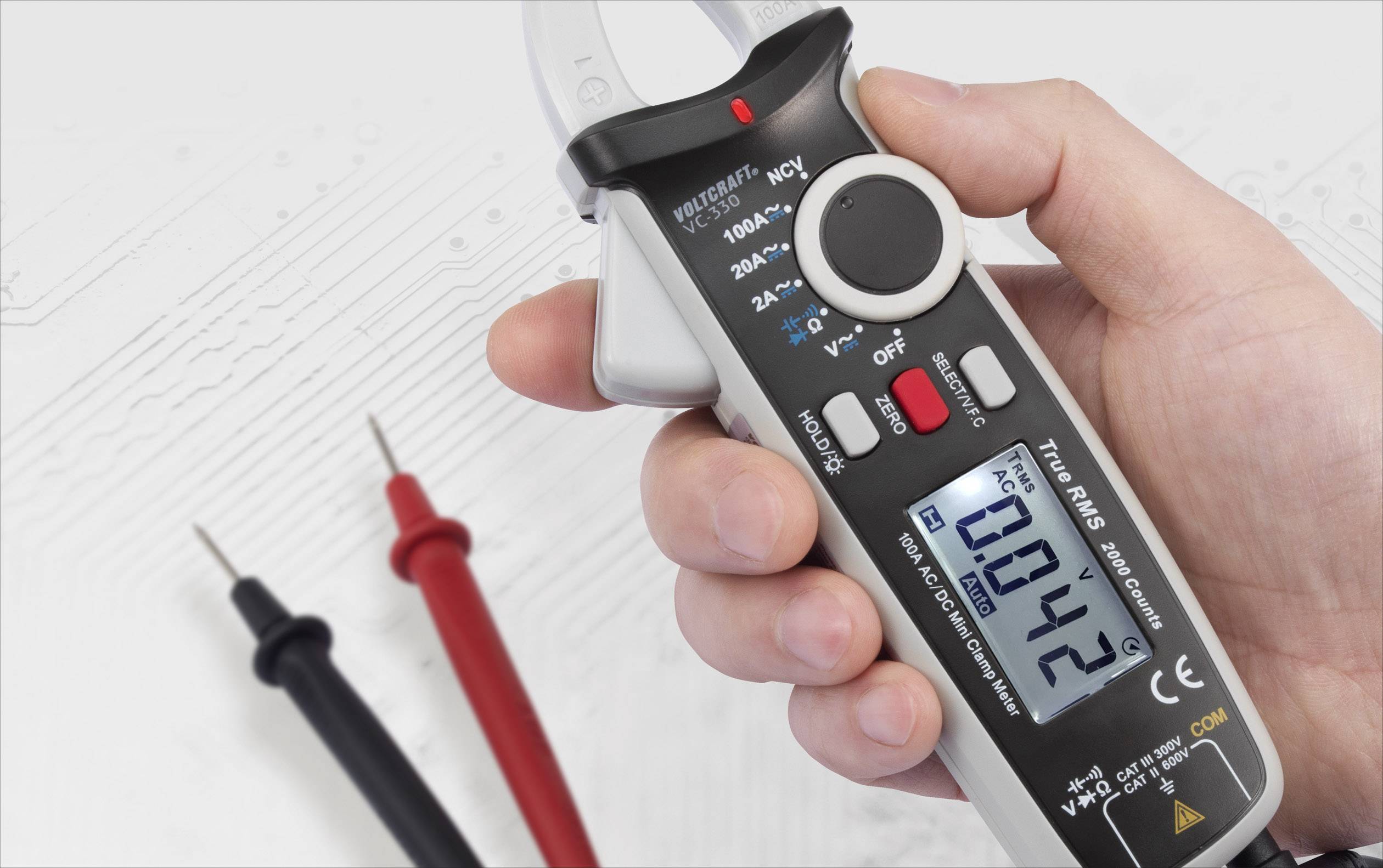 Eine Hand hält einen digitalen Stromzangen-Multimeter, das 0,42 auf dem Display anzeigt. Daneben sind zwei Messleitungen sichtbar.