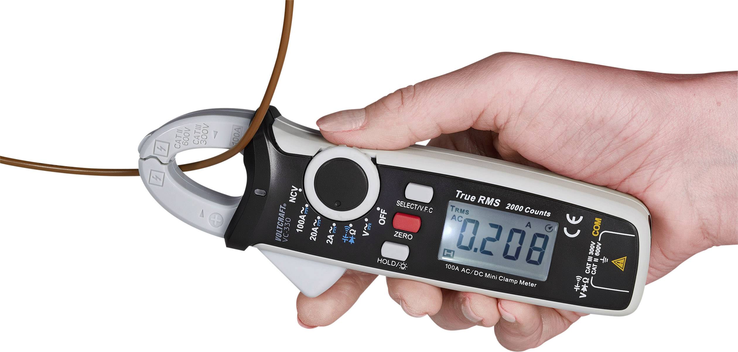Eine Hand hält ein digitales Strommessgerät, das den Wert '0,208' anzeigt, während es einen braunen Draht umschließt.