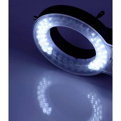 Ein Ringlicht mit strahlend weißem LED-Licht liegt auf einer spiegelnden Oberfläche, wobei das Licht einen kreisförmigen Reflex erzeugt.