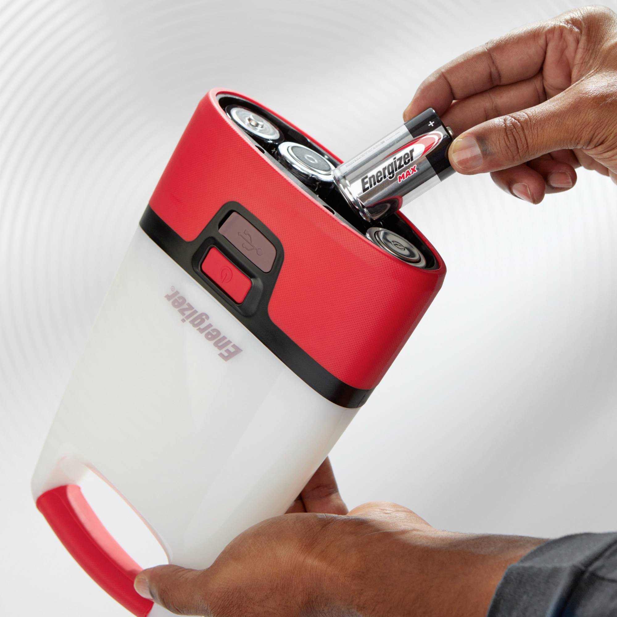 Eine Hand legt eine Energizer-Batterie in eine rote Taschenlampe ein. Die Taschenlampe ist aufrecht und leicht geneigt.