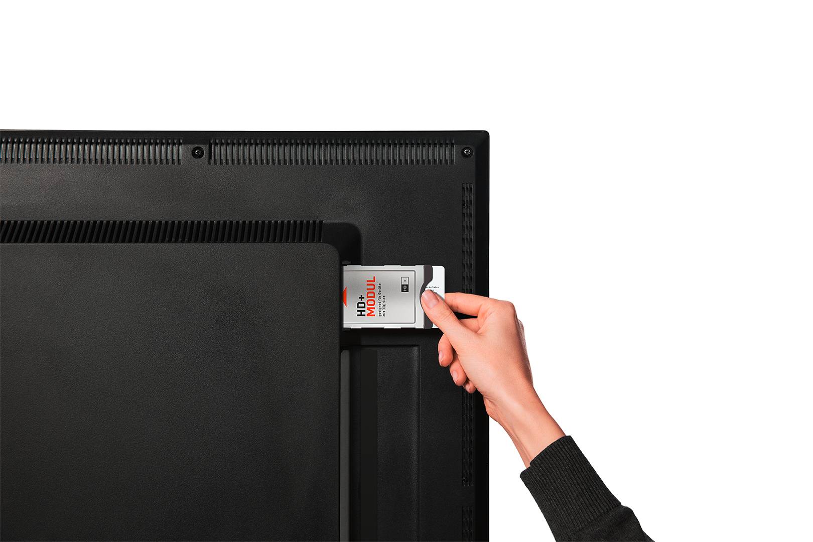 Eine Hand schiebt ein CI+-Modul 'HD+ Modul' in den Kartensteckplatz auf der Rückseite eines Fernsehers.