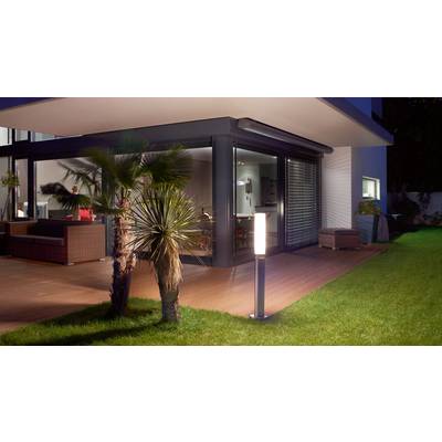 Ein modernes Haus mit einer Terrasse aus Holz, beleuchtet von Außenlampen. Pflanzen und Gartenmöbel schaffen eine gemütliche Atmosphäre.
