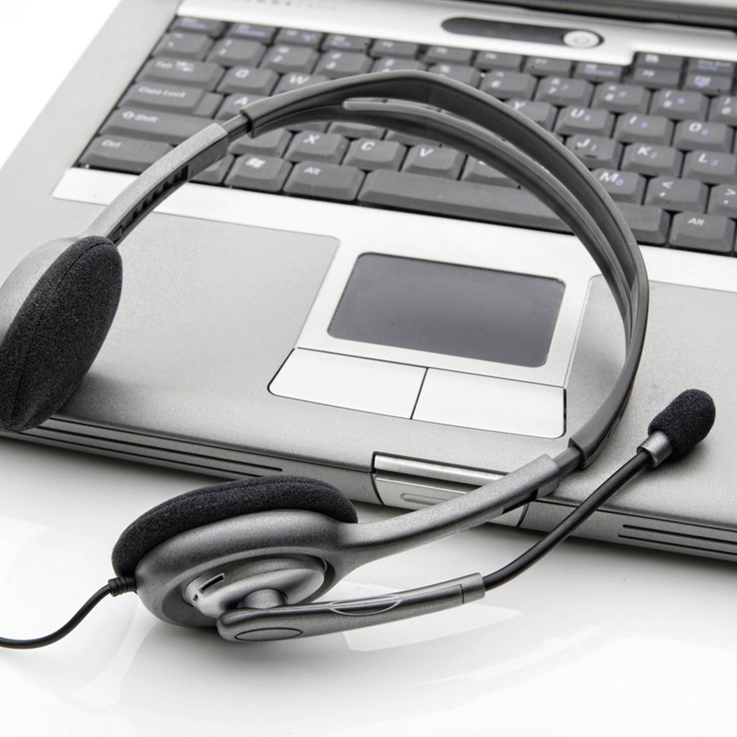 Headset liegt auf Tastatur eines Laptops, bereit für eine Online-Konferenz.