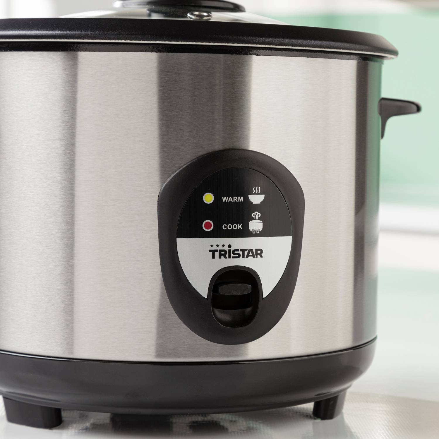 Ein silberner Reiskocher mit schwarzem Deckel und Bedienfeld. Zeigt Betriebsanzeigen 'Warm' und 'Cook' sowie das Logo 'Tristar'.