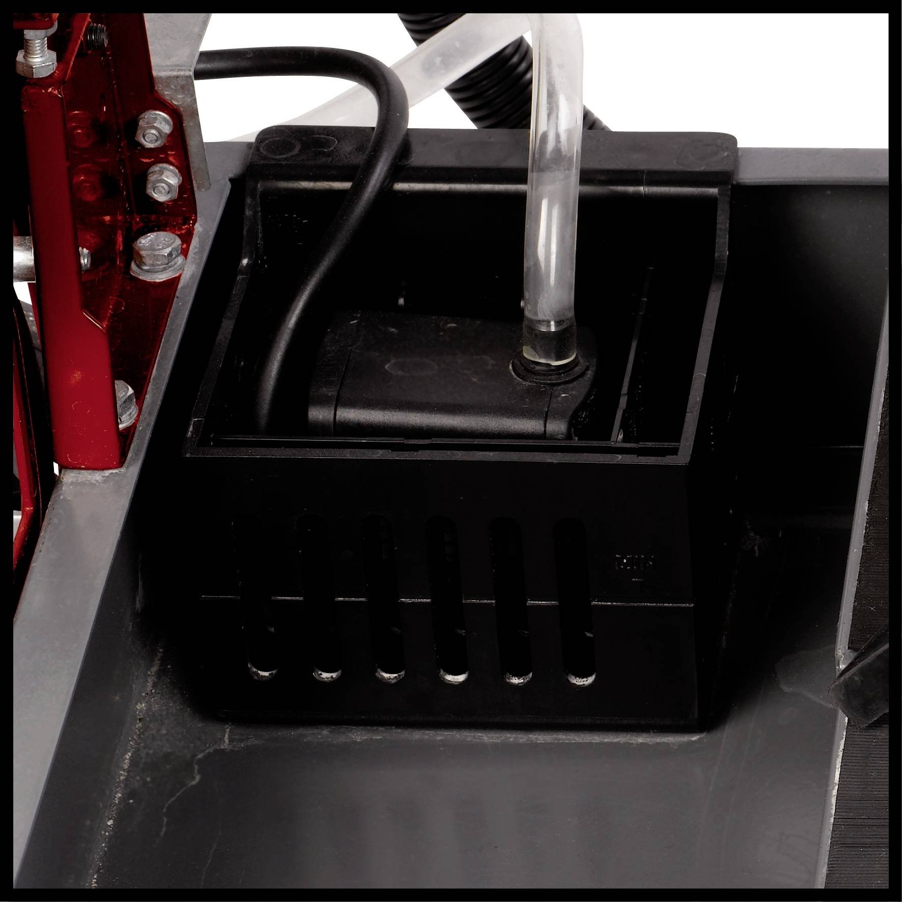 Eine schwarze Wasserpumpe in einem Gehäuse ist in einer metallischen Umgebung montiert. Ein transparenter Schlauch führt zur Pumpe.