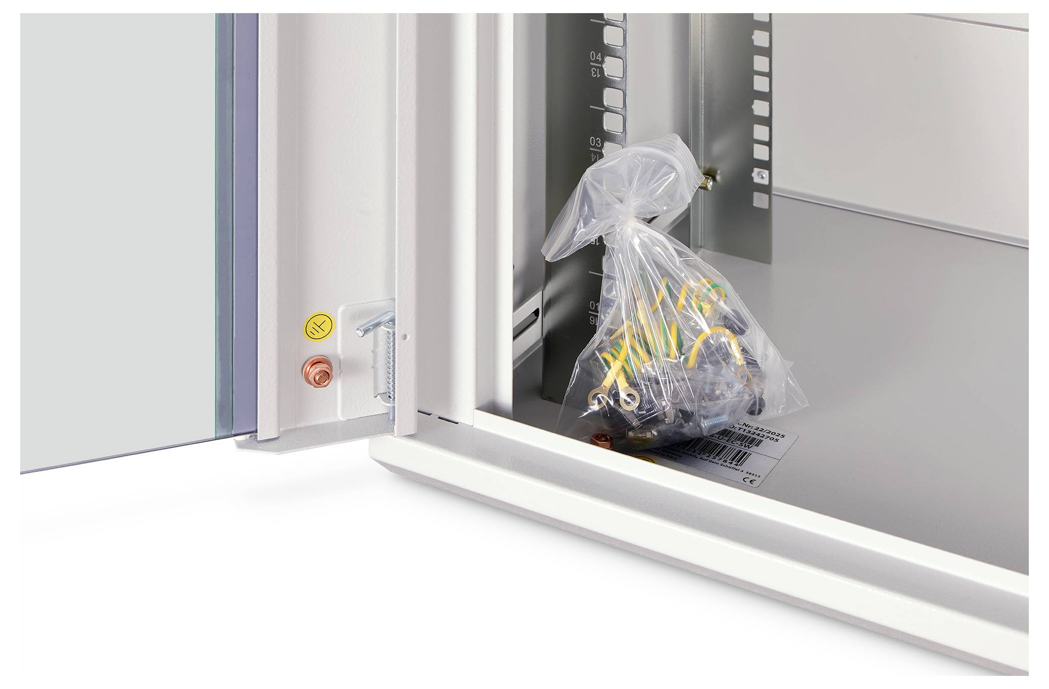 Eine Plastiktüte mit Schrauben und kleinen Teilen wird in einem offenen Metallschrank mit sichtbaren Scharnieren und Beschriftung abgelegt.