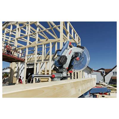 Eine Kreissäge schneidet einen Holzbalken auf einer Baustelle zum Hausbau unter klarem blauem Himmel.
