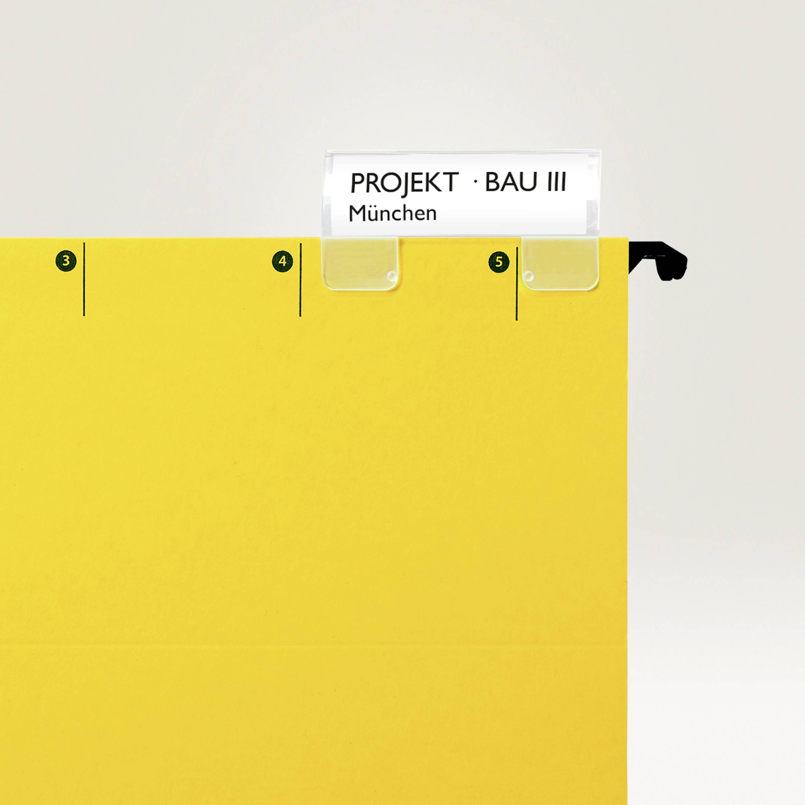 Gelber Ablageordner mit Registerkarten. Oben stecken weiße Karteikarten mit der Aufschrift 'PROJEKT · BAU III München'.