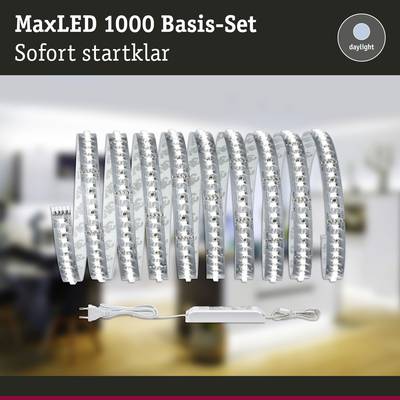 'MaxLED 1000 Basis-Set' LED-Streifen mit Netzteil und Fernbedienung im Hintergrund eines unscharfen Wohnzimmers, Text 'Sofort startklar'.