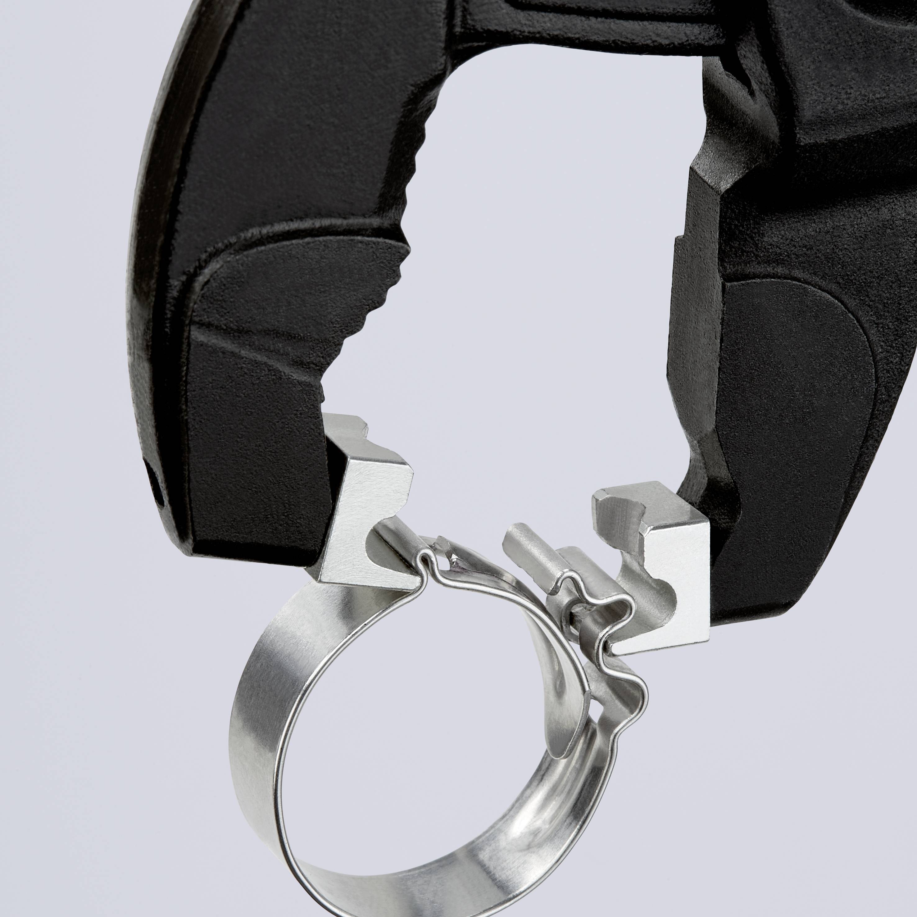 Metallobjekt mit schwarzem Detail, evtl. Teil eines Mechanismus, auf hellblauem Hintergrund.