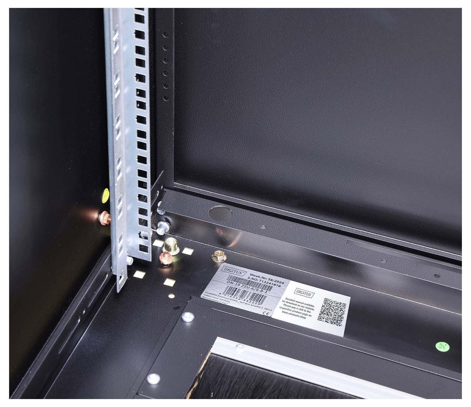 Innenansicht eines schwarzen Metallschranks mit montiertem Halterahmen und sichtbarem Etikett mit QR-Code.