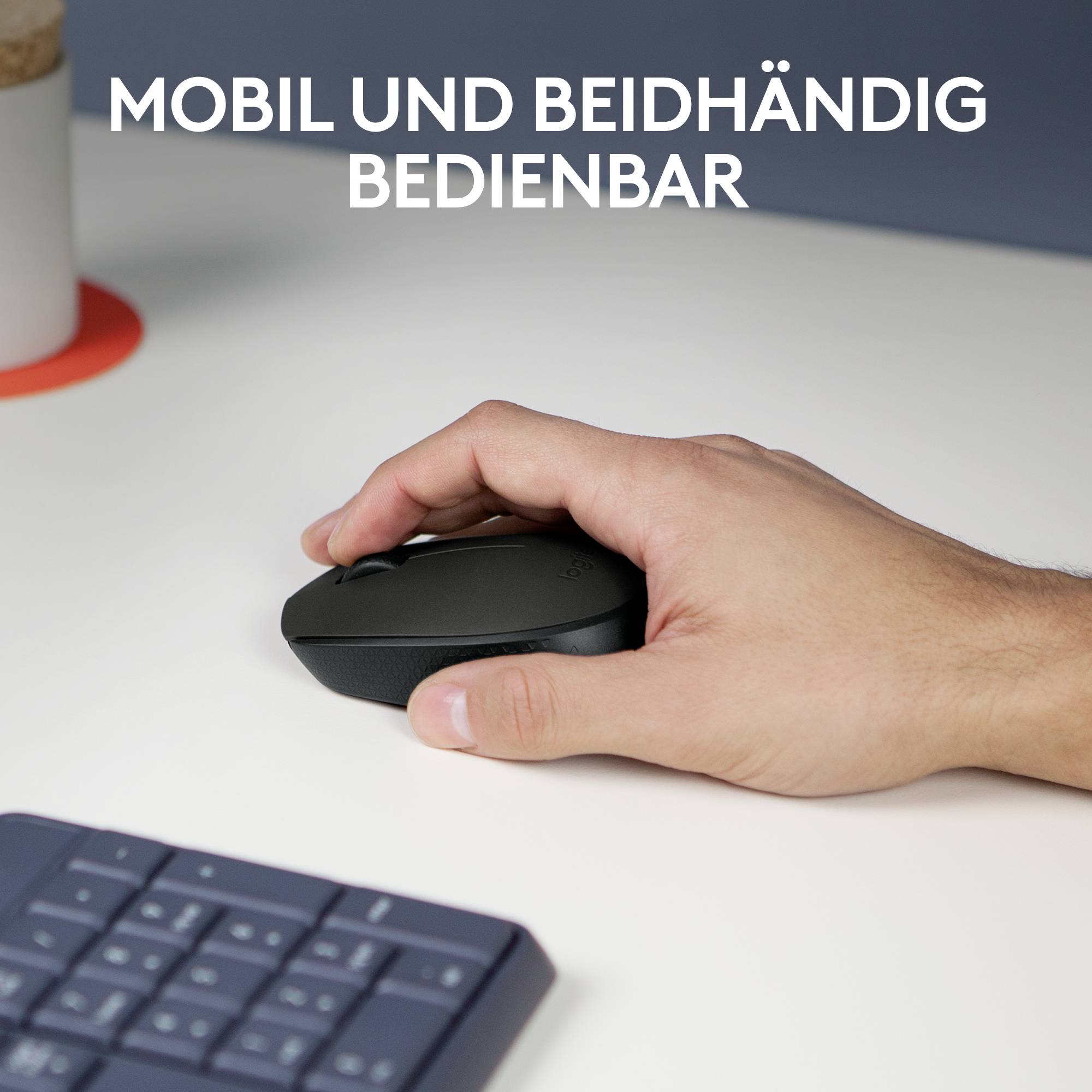 Eine Hand hält eine Maus auf einem Schreibtisch. Im Hintergrund ist eine Tastatur teilweise sichtbar. Text oben: 'Mobil und beidhändig bedienbar'.
