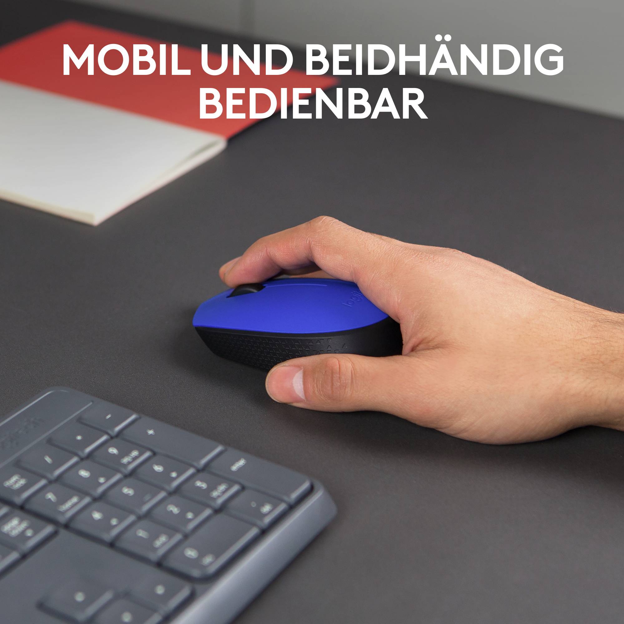 Ein Tisch mit Tastatur, schwarzer und blauer kompakter Maus. Eine Hand greift die Maus. Text: 'MOBIL UND BEIDHÄNDIG BEDIENBAR'.