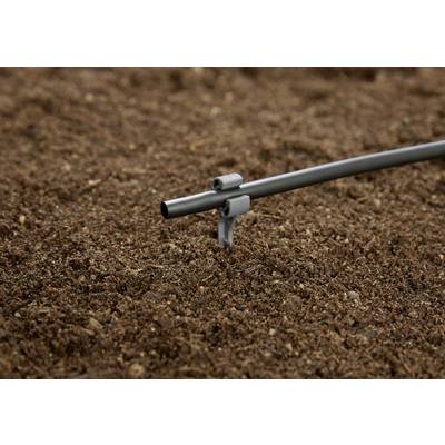 Ein graues Bewässerungsrohr ragt aus der braunen Erde, bereit zur Pflanzenbewässerung im Garten.