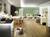 Ein modernes Wohnzimmer mit Laminatboden, sofa auf grün gestrichenem Hintergrund, Esstisch mit Stühlen und einem Arbeitsbereich.