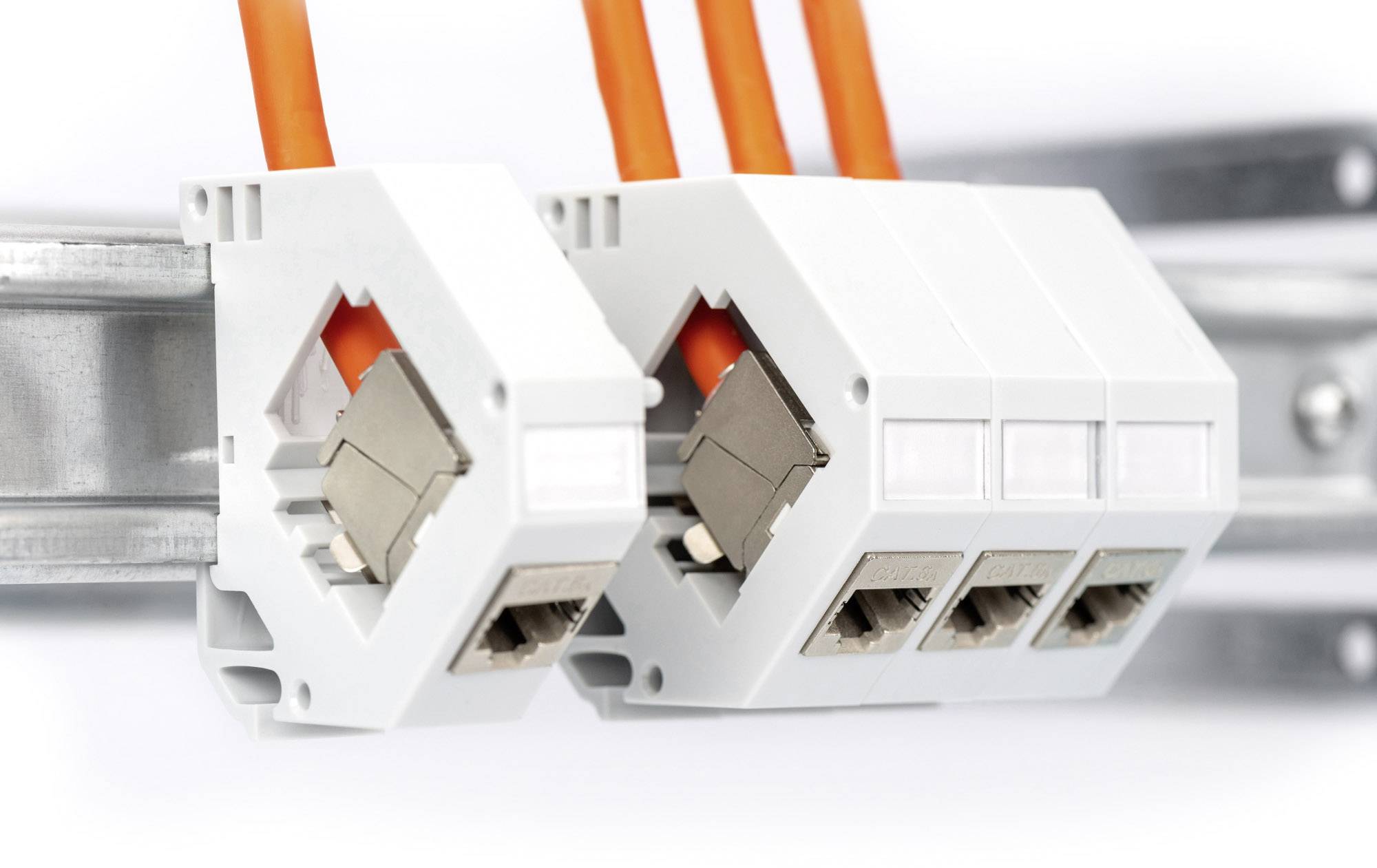 Zwei weiße Elektroanschlussklemmen mit orangefarbenen Drähten montiert auf einer Schiene, symbolisieren elektrische Verkabelung.