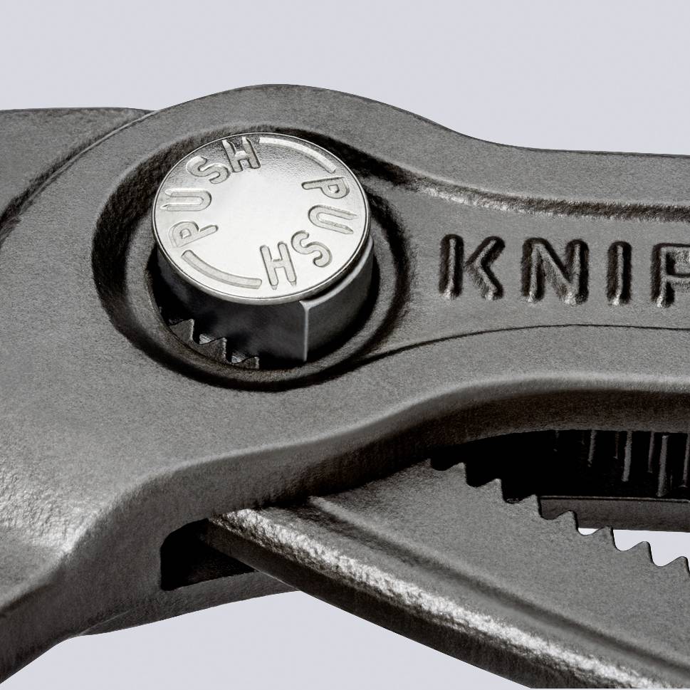 Nahaufnahme eines Metallwerkzeugs mit einem Drehknopf, auf dem 'PUSH' steht. Die Oberfläche hat eine graue, strukturierte Oberfläche.