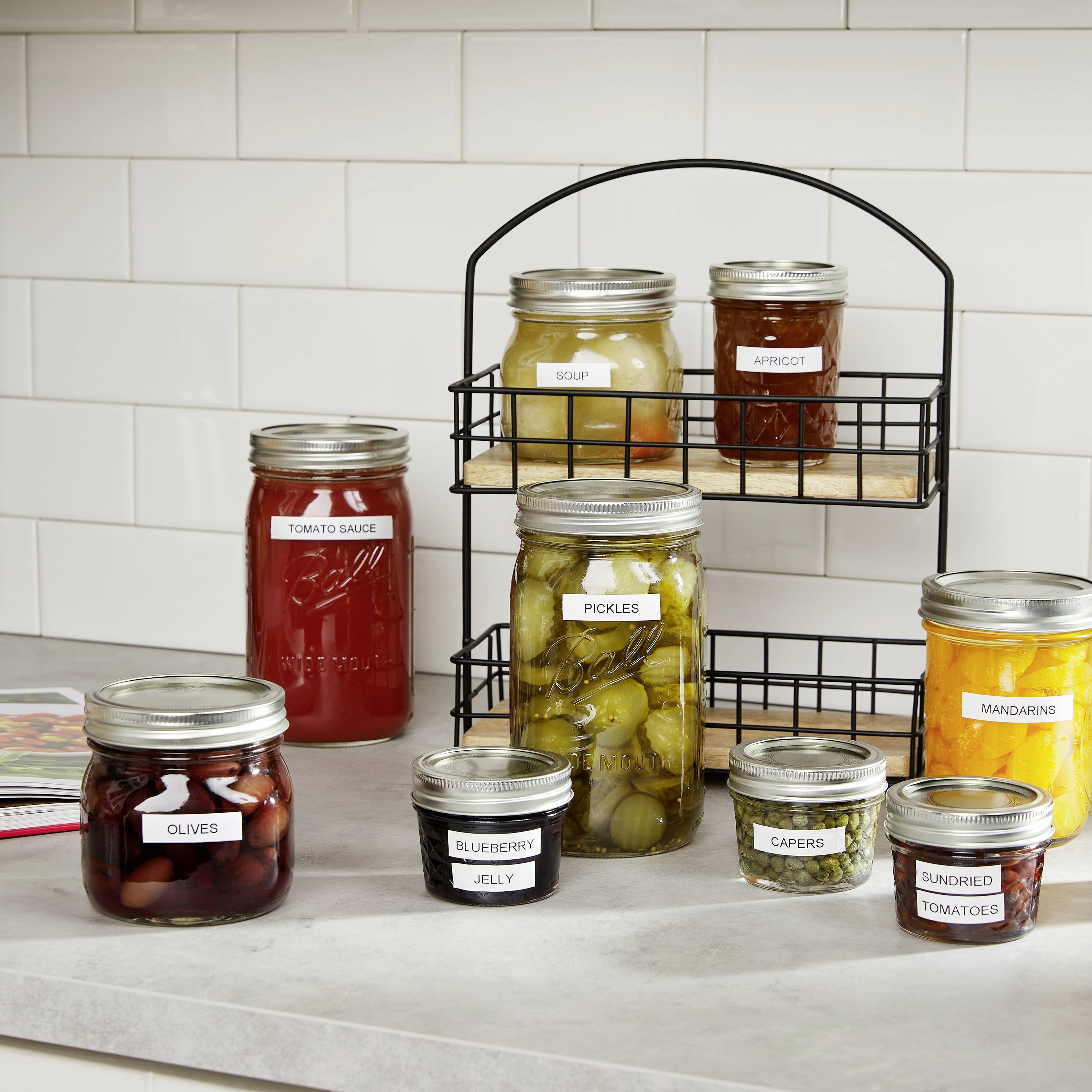 Ein Küchentresen mit verschiedenen Gläsern gefüllt mit Suppe, Marmelade, Oliven, Tomatensauce und anderen eingelegten Lebensmitteln.