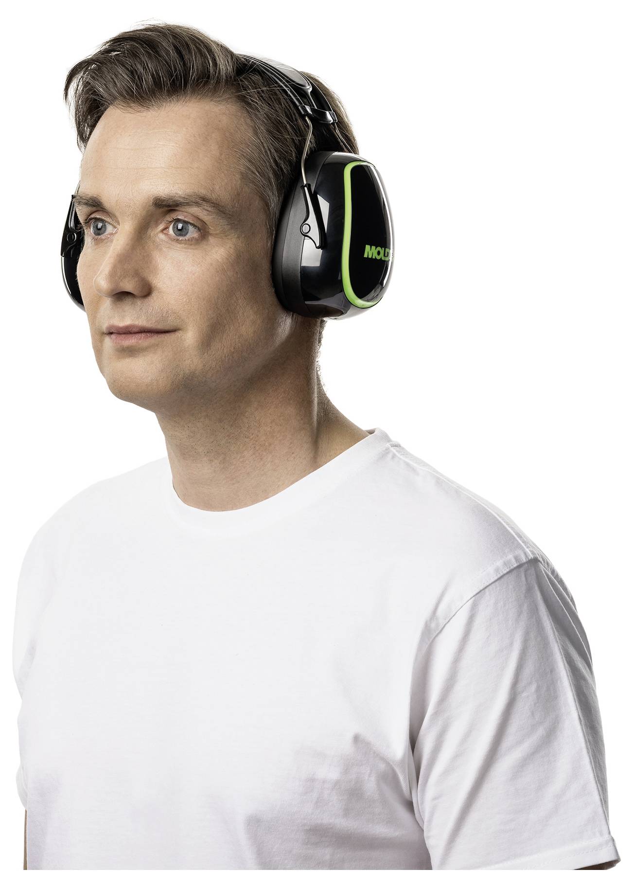 Eine Person, die schwarze und grüne Geräuschunterdrückungsohrmuscheln trägt, wirkt nachdenklich, gekleidet in ein weißes T-Shirt vor einem einfachen Hintergrund.