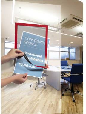 Eine Person entfernt ein Schild mit der Aufschrift 'CONFERENCE ROOM III International Business Meeting 10.00 a.m.' von einer Glastür in einem modernen Konferenzraum.