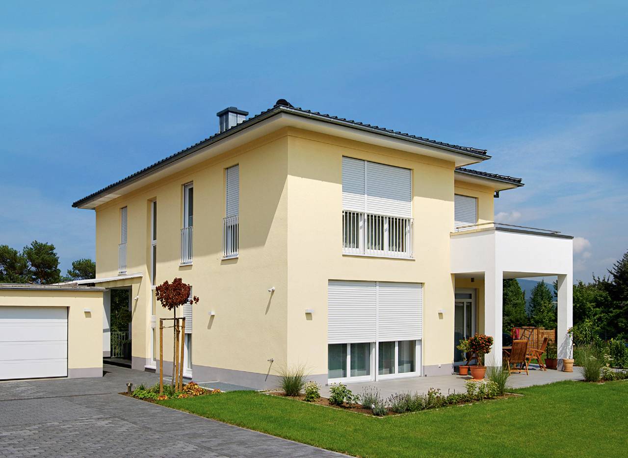 Ein modernes zweistöckiges Einfamilienhaus mit gelber Fassade und großen Fenstern, umgeben von einem gepflegten Garten bei sonnigem Wetter.