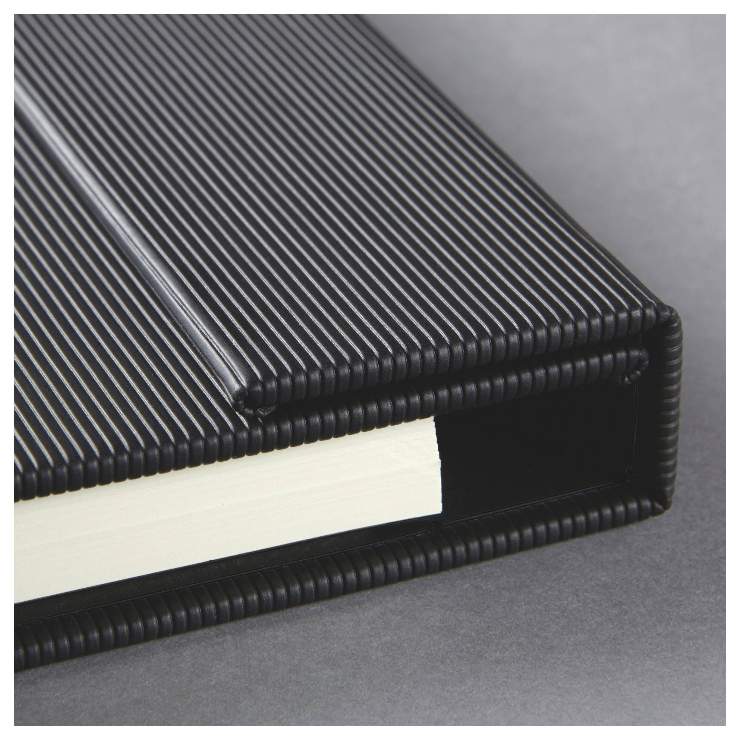 Nahaufnahme eines schwarzen gerippten Ordners oder einer schwarzen gerippten Box, die ein dickes weißes Buch oder Dokument hält, das teilweise vor einem grauen Hintergrund eingeschoben ist.