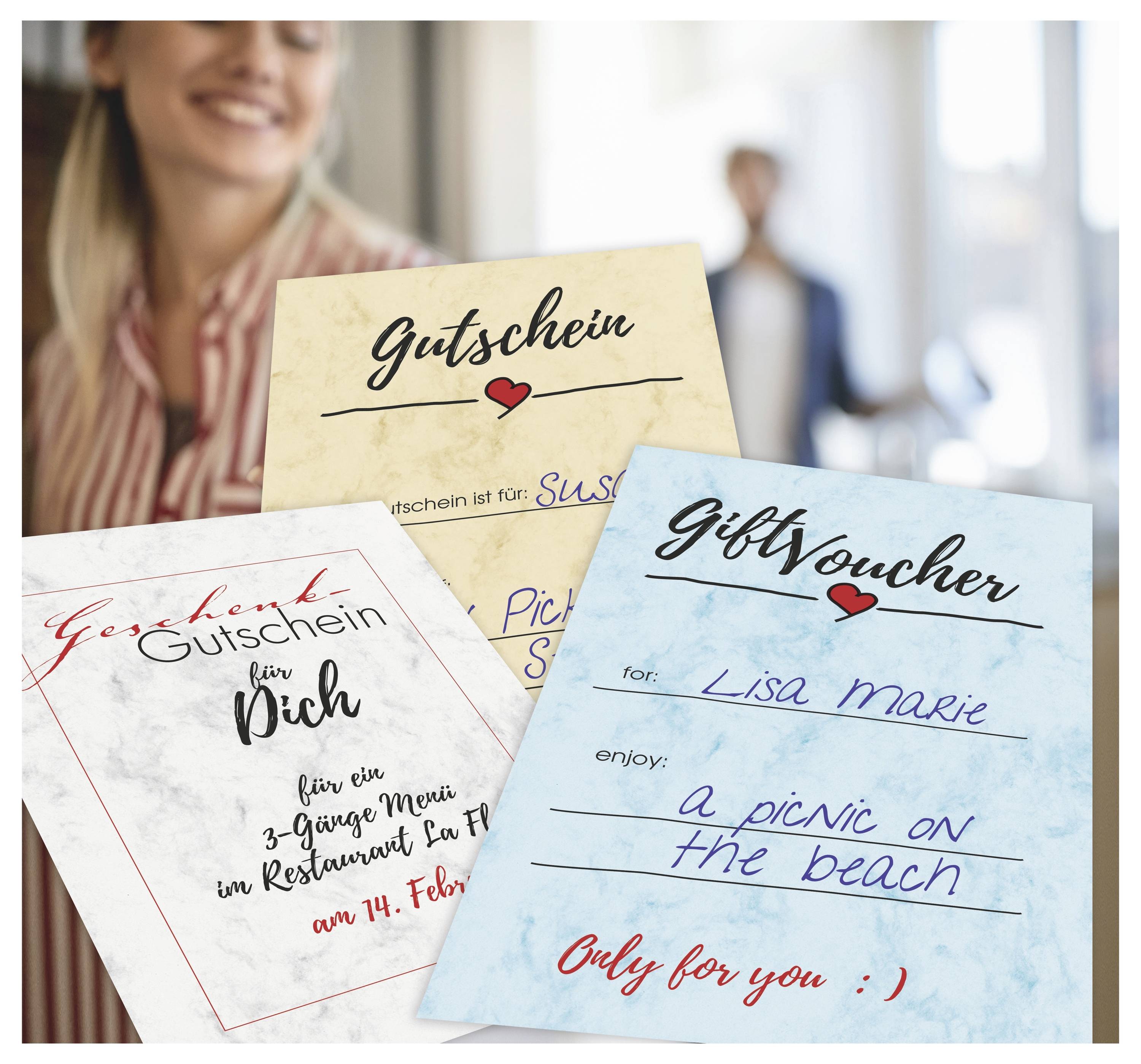Drei handschriftliche Geschenkgutscheine, einschließlich "Gutschein" und "Geschenkgutschein", gehalten von einer lächelnden Frau mit einer unscharfen Hintergrundfigur in Innenräumen.