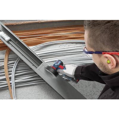 Eine Person in Schutzausrüstung schneidet eine Metallleitung mit einem Elektrowerkzeug, umgeben von sorgfältig angeordneten Elektrokabeln.