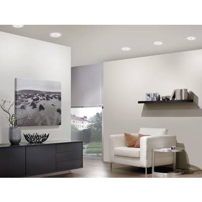 Ein modernes Wohnzimmer mit weißen Wänden, einem weißen Sessel, braunem Kissen, Wandbild, Bücherregal und Fenster mit Außenblick.