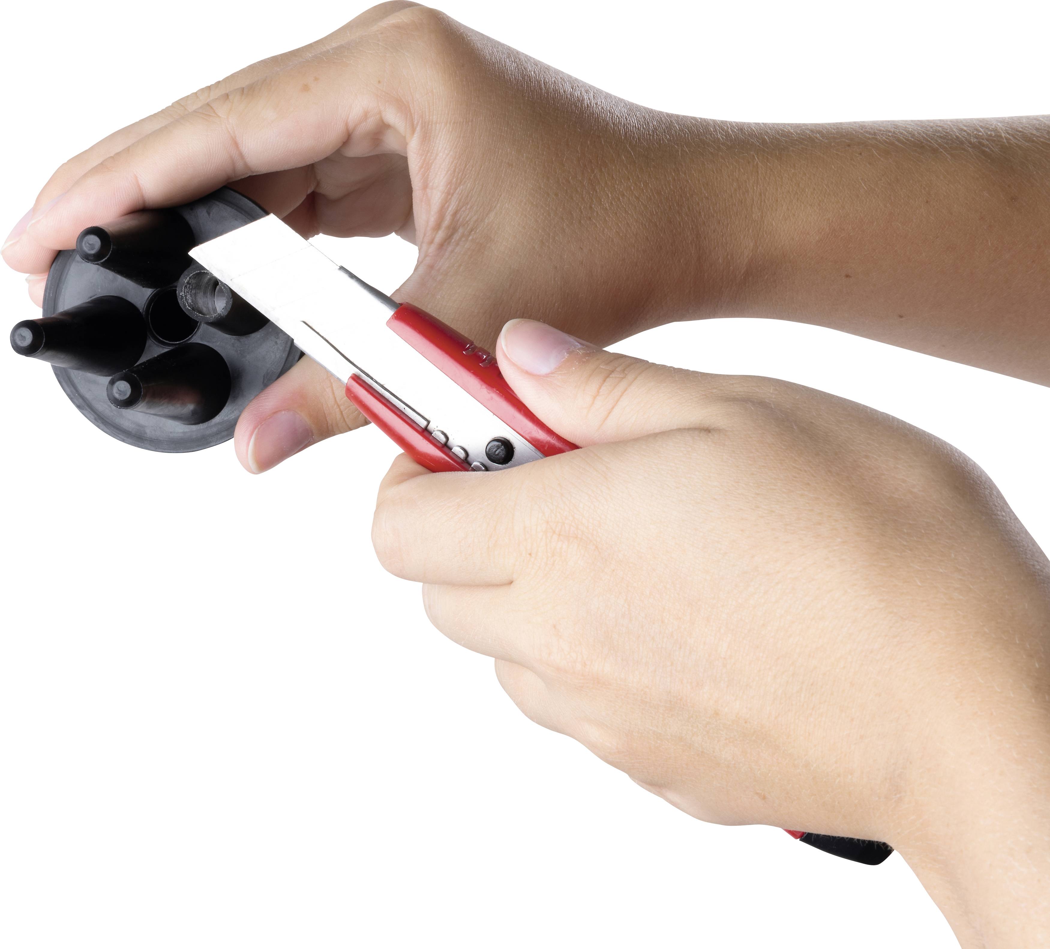 Eine Person hält ein sechseckiges schwarzes Objekt in der einen Hand und ein rot-weißes Cutter-Messer in der anderen Hand.