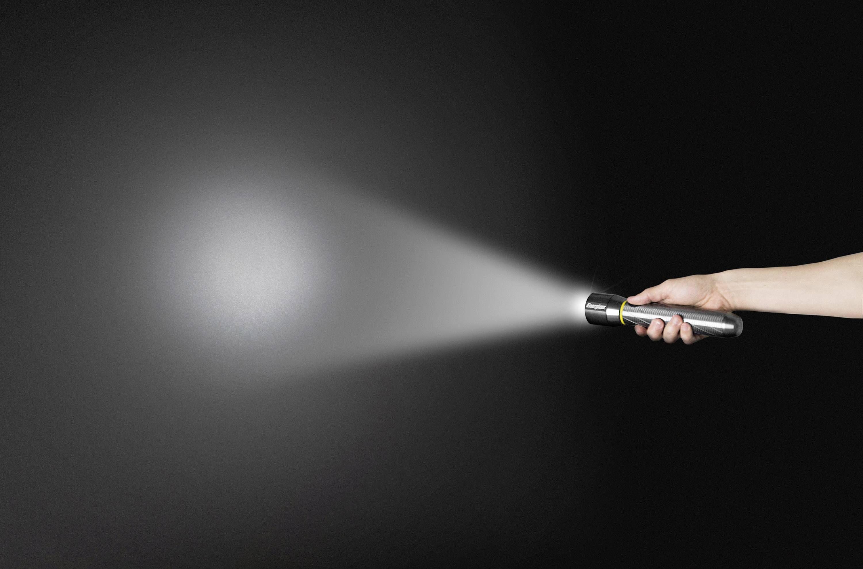 Eine Hand hält eine Taschenlampe, die einen Lichtstrahl auf eine dunkle Fläche wirft.