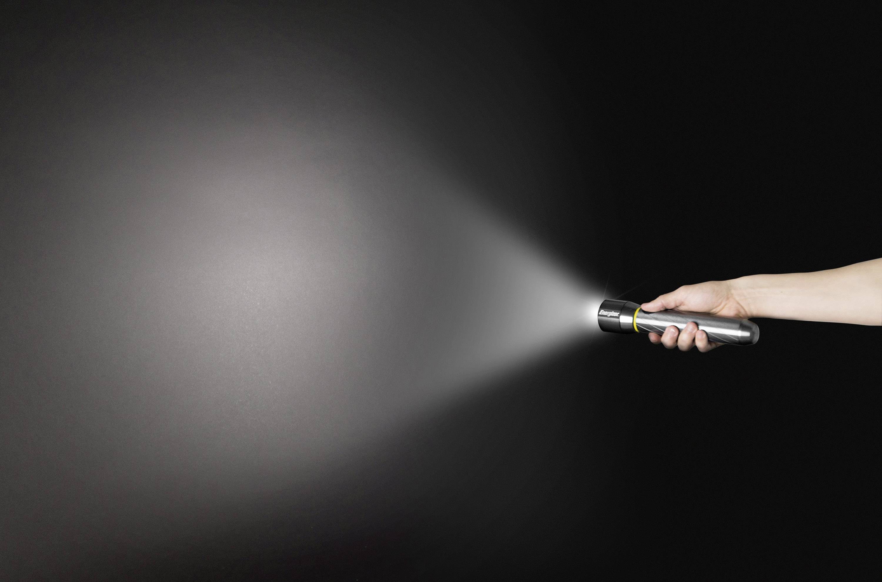 'Eine Hand hält eine Taschenlampe, die in einem dunklen Raum leuchtet. Der Lichtstrahl ist klar sichtbar auf der schwarzen Wand.'