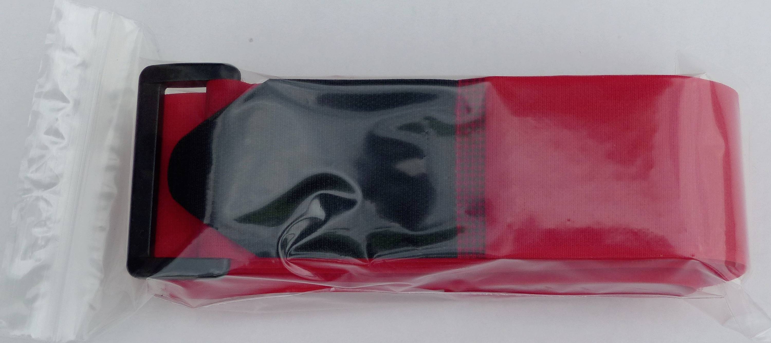 Ein schwarzer Gürtel in einer roten Kunststoffverpackung, teilweise geöffnet.
