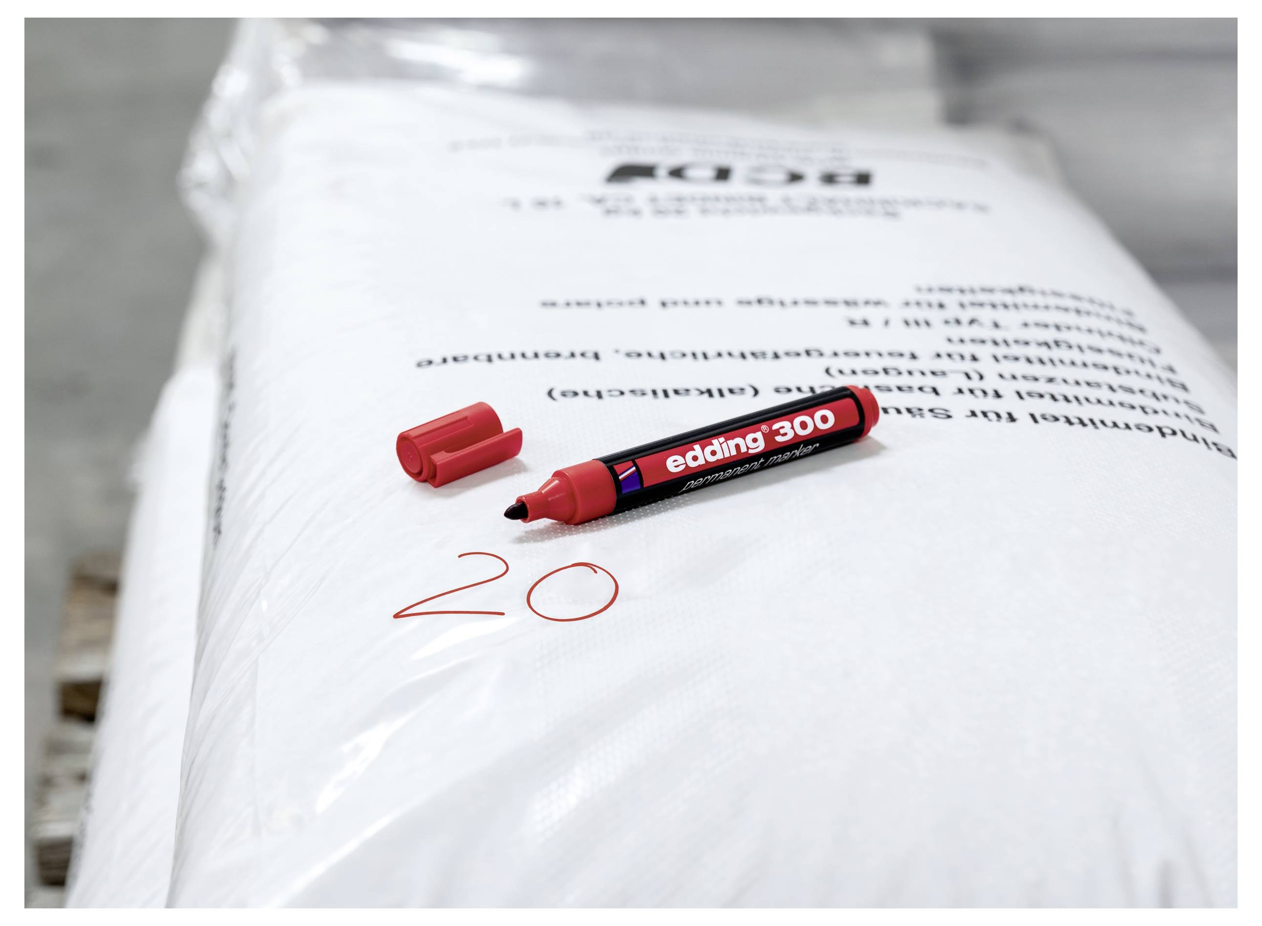 Roter Marker und Kappe auf einem weißen Paket, mit handschriftlich geschriebener "20" in Rot in der Nähe des unteren Randes.