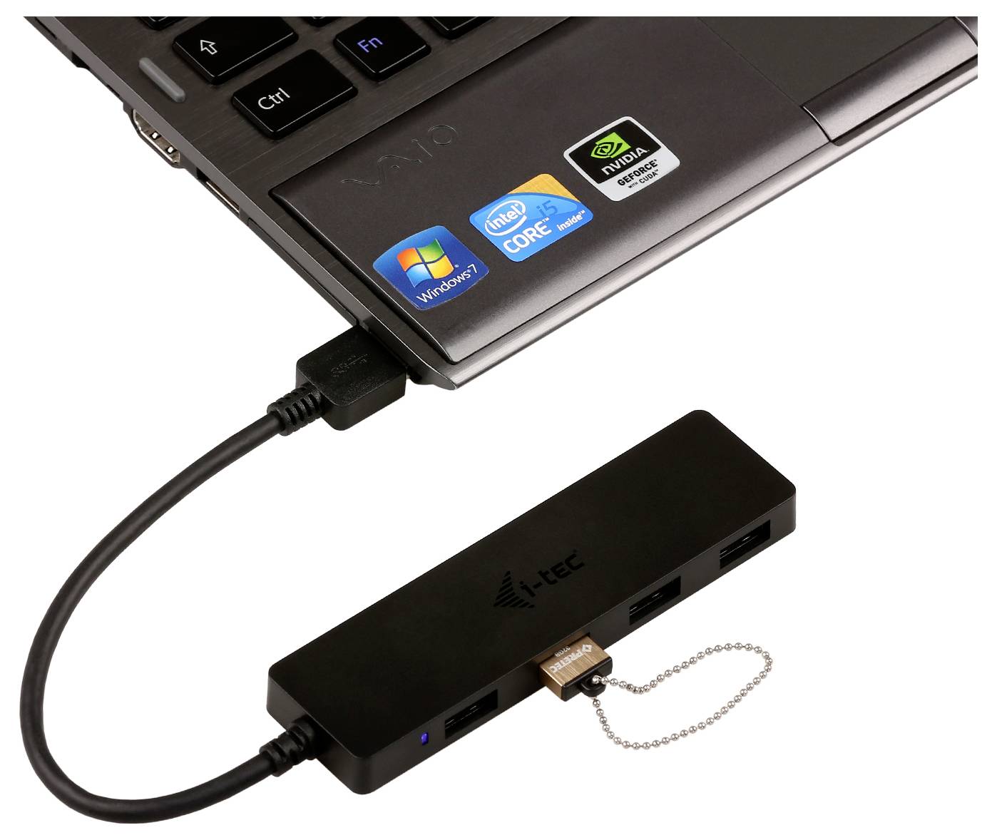 Ein schwarzer i-Tec USB-Hub mit mehreren Anschlüssen, der mit einem Laptop verbunden ist. Der Laptop hat Aufkleber für Windows 7, Intel Core und NVIDIA.