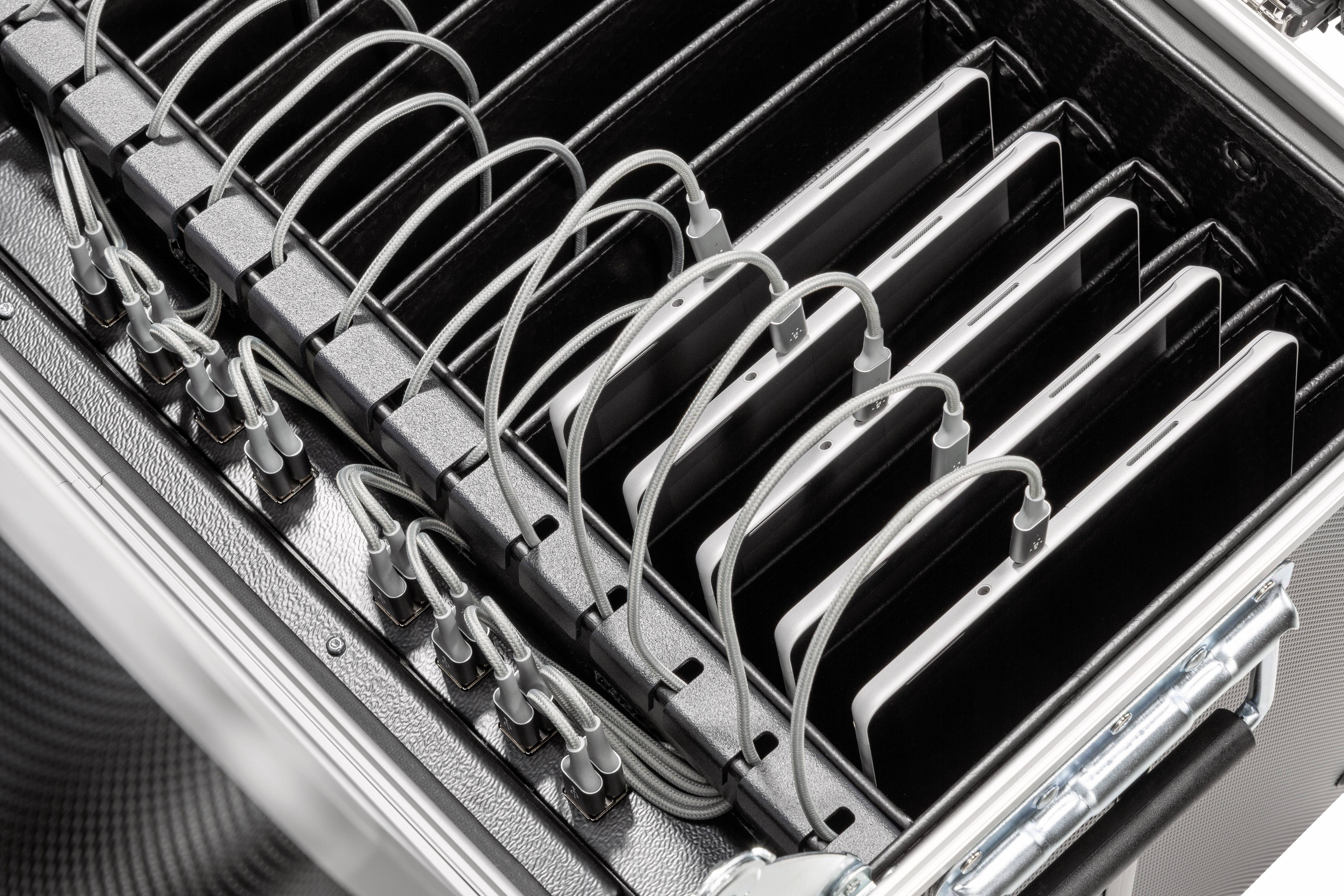 Tabletts in einem Koffer, mit mehreren Ladekabeln angeschlossen. Der Koffer scheint für die gleichzeitige Aufladung mehrerer Geräte ausgelegt.